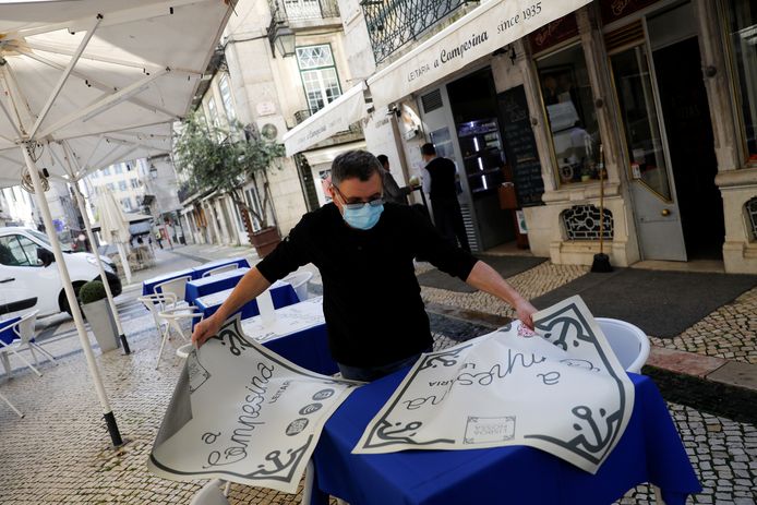 Een horeca-uitbater maakt zijn terras klaar in Lissabon.