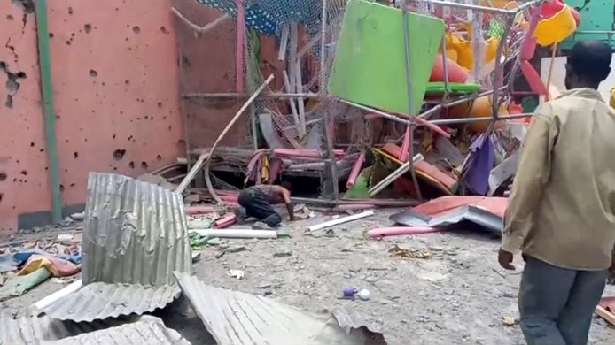 Un homme se penche afin d'inspecter les décombres du jardin d'enfants visé par l'attaque.
