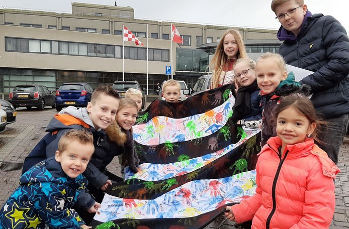 Kinderen van basisschool De Kiem met hun spandoek vóór het gemeentehuis van Bernheze.