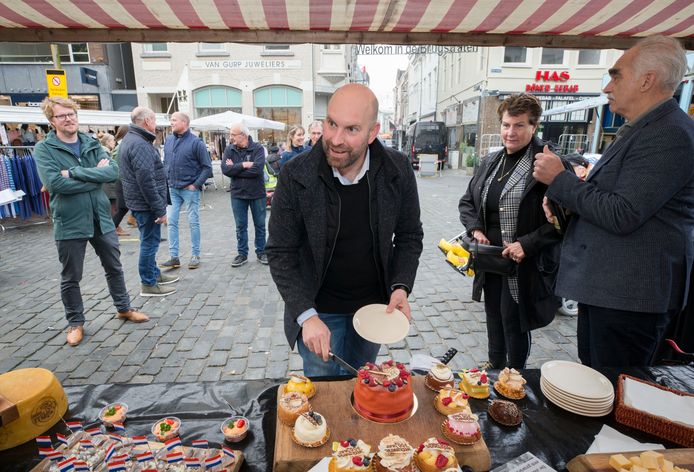 Wethouder Boaz Adank snijdt op de verjaardag van de zevenhonderdjarige dinsdagmarkt een taartje aan. Rechts: Peter Dillisse naast Louise Wesselius.