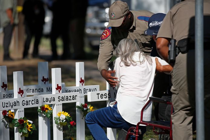 Politiemensen helpen een vrouw die haar medeleven komt uiten bij de herdenkingsplek voor de slachtoffers van de mass-shooting in Texas.