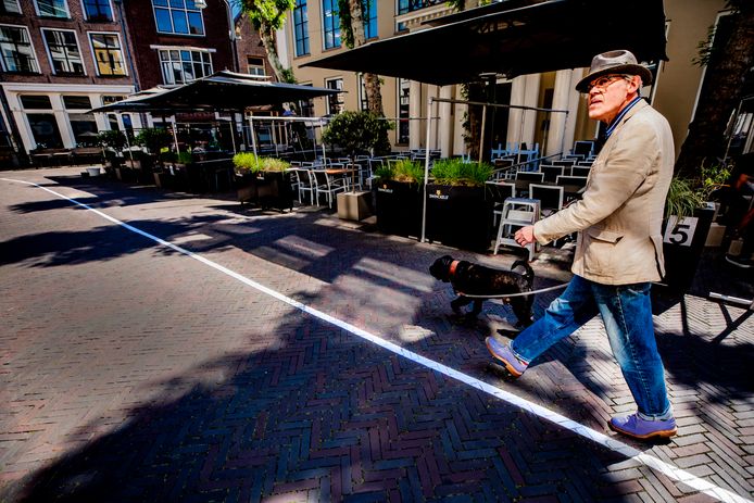 Een man laat zijn hond uit op de Grote Poot in Deventer. Hij blijft keurig aan de rechterkant van de streep, zoals het bedoeld is.