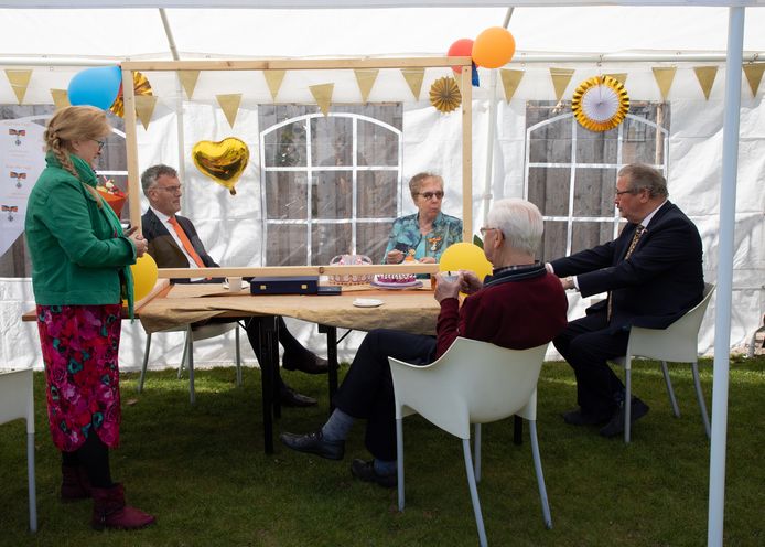 Burgemeester Janssen schuift voor het lintje voor Els Mommers-Van Tuyl aan in de partytent