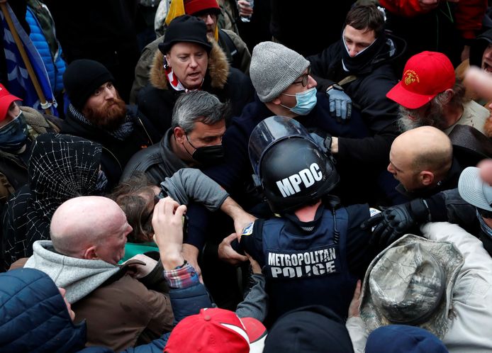 Een agent van de Metropolitan Police van Washington DC wordt compleet omsingeld door demonstranten.