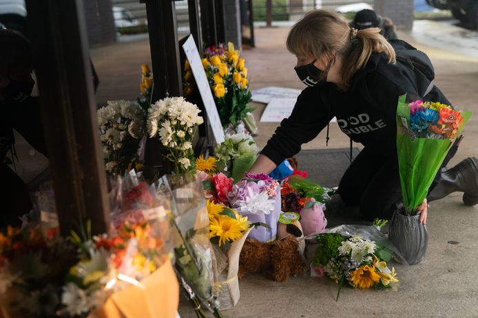Een vrouw legt bloemen neer aan een van de massagesalons waar gisteren vier personen werden doodgeschoten in Atlanta.