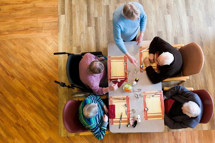 Een vrijwilligster serveert eten in een verzorgingshuis.