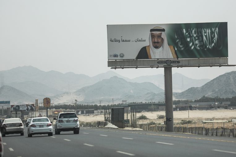 Auto's rijden langs een bord met de afbeelding van koning Salman Beeld AP