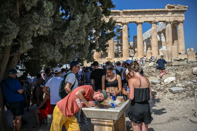 Toeristen zoeken verkoeling bij een waterfonteintje tijdens hittegolf in Athene, Griekenland op 14 juli 2023.