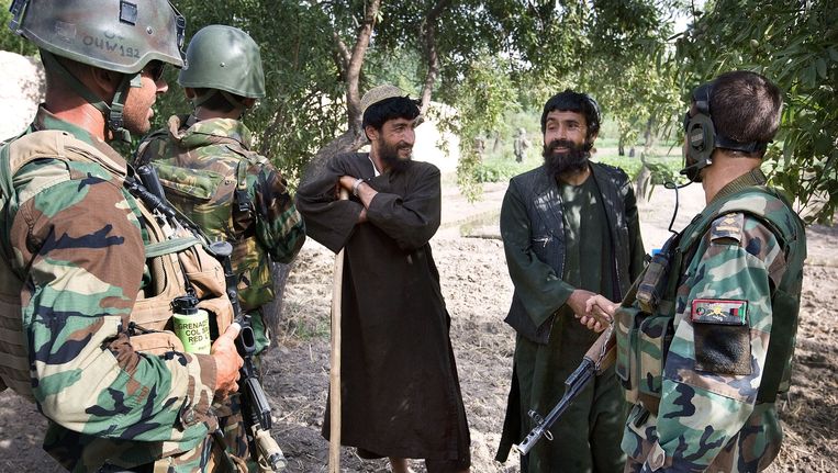 Een Nederlandse sergeant majoor (links) praat met Afghaanse boeren in Deh Refshan in de Balouzi Vallei. De andere twee soldaten zijn Afghaanse tolken, waarvan sommige een tijd als vluchteling in Nederland heebben gewoond. Beeld Guus Dubbelman / de Volkskrant