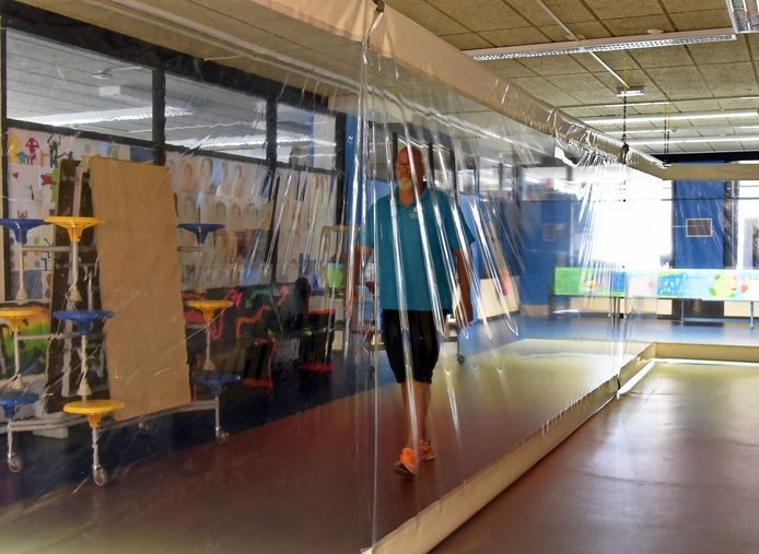 Concierge Sjoerd van Helmond van het Lodewijk College in Terneuzen loopt door de gang die afgescheiden is met plastic. Eenrichtingverkeer was hier niet mogelijk.