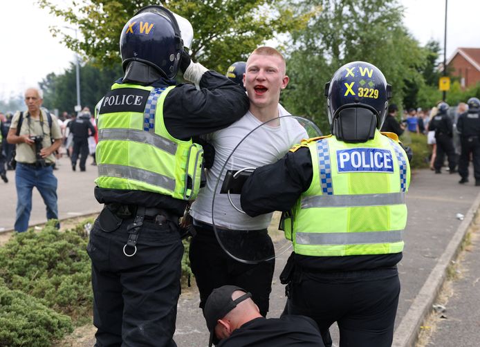 De politie leidt een relschopper weg.