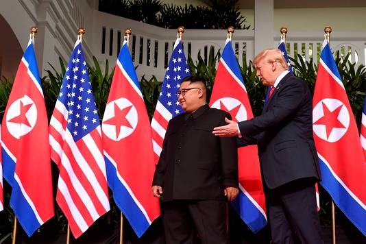 Trump wijst Kim de weg, een hand op zijn rug.
