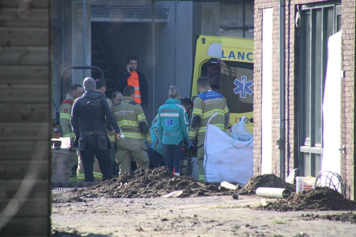 Brandweerlieden en ambulancepersoneel tillen de gewonde uit de woning.