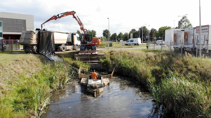 Baggerwerkzaamheden: het slib wordt via een schuifboot naar een plek geduwd waar het met een hijskraan uit de boot wordt gevist.