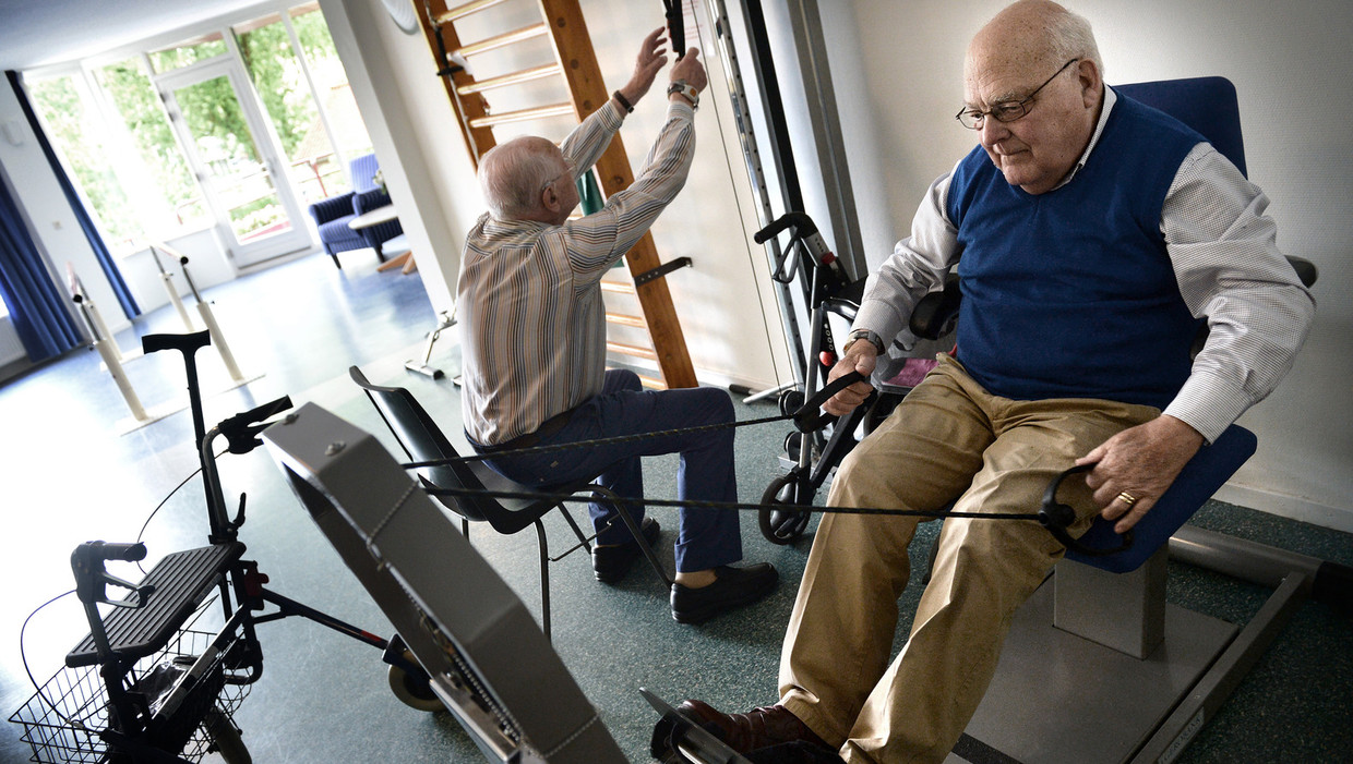 De 84-jarige meneer Martens (rechts) tijdens zijn dagelijkse halfuur trainen in de fitnessruimte van Godelinde, een voormalig verzorgingshuis in Bussum. Beeld Marcel van den Bergh / de Volkskrant