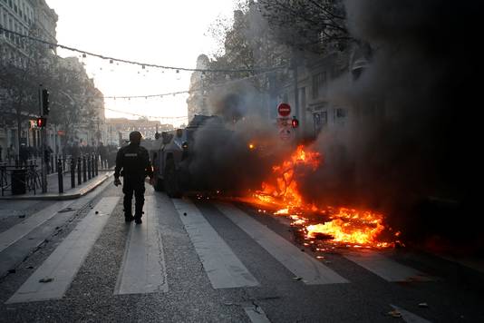 Een pantserwagen van de Franse politie duwt een brandende auto weg in Marseille.