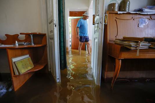 Een man in zijn overstroomd huis in Cherson.