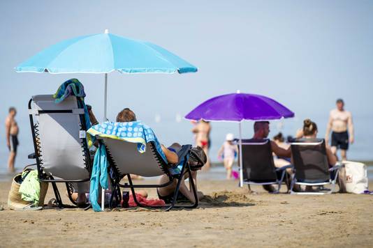 Badgasten op het strand. Nu er een periode met zonnig en heet zomerweer is aangebroken, zijn mensen op zoek naar verkoeling.