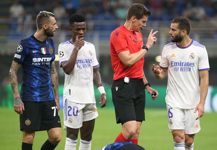 Siebert geeft uitleg aan Nacho nadat hij die heeft teruggefloten na een overtreding in de Champions League-match tussen Inter en Real. Brozovic (links) en Vinicius kijken toe.