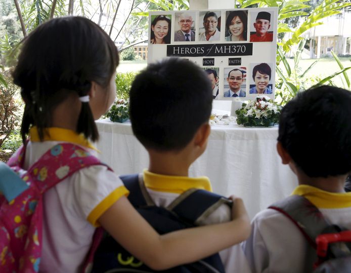 Kinderen in Kuala Lumpur kijken naar foto's van de passagiers van vermiste passagiers van MH370
