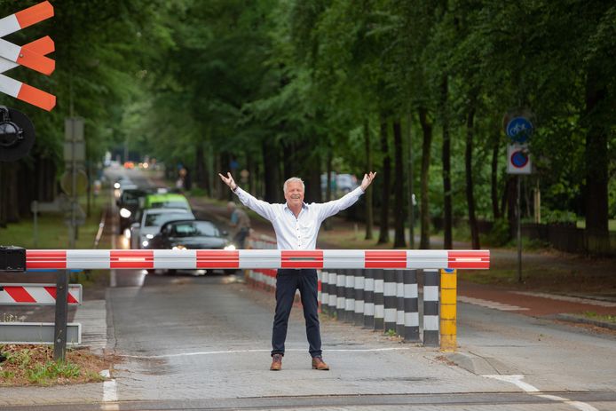 De Baarnse restauranthouder Ruud Bouwman regelt het verkeer langs de dichte spoorbomen.
