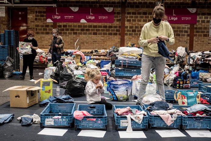 In Angleur, Luik, snuisteren een kind en een vrouw in een schuilplaats tussen geschonken kledij.