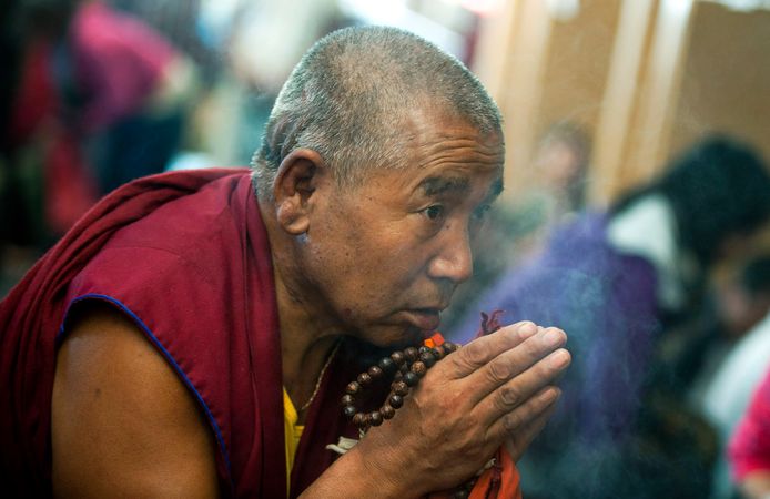 Een Tibetaanse boeddhistische monnik  in India bidt in de richting van het raam waarachter de Dalai Lama een religieuze toespraak houdt in de tempel van Dharmsala, India. Archieffoto.