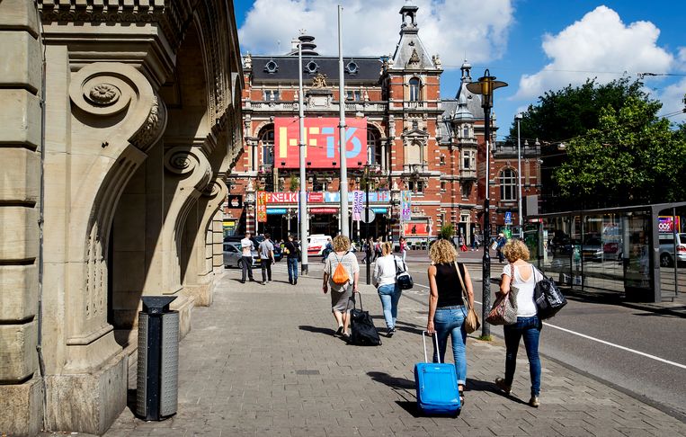 Toeristen met rolkoffers op het Leidseplein in Amsterdam. Velen van hen verbleven in een huis gehuurd via Airbnb. Beeld ANP, Koen van Weel