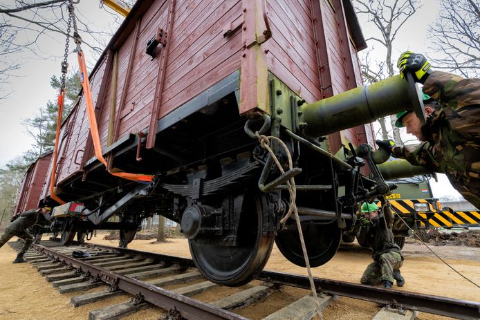 Voorzichtig wordt de tweede wagon op de rails gezet bij Nationaal Monument Kamp Vught.