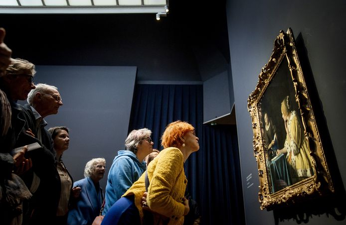 Bezoekers bestuderen Dame en dienstmeid van Johannes Vermeer tijdens de opening van de Vermeertentoonstelling in het Rijksmuseum.