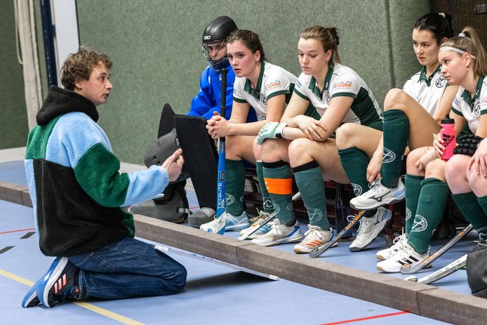 Coach Lucas Westra van MHC Bemmel spreekt het team toe in de rust van het duel met Drienerlo. Ook Lia Otten (met oranje band) luistert aandachtig.