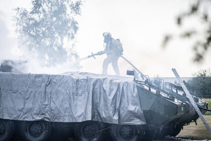 Een brandweerman klimt op het pantservoertuig om te blussen.