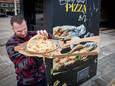 Italiaanse pizzachef Simone keurt met een bedenkelijke blik de pizza uit de automaat bij Shell tankstation.