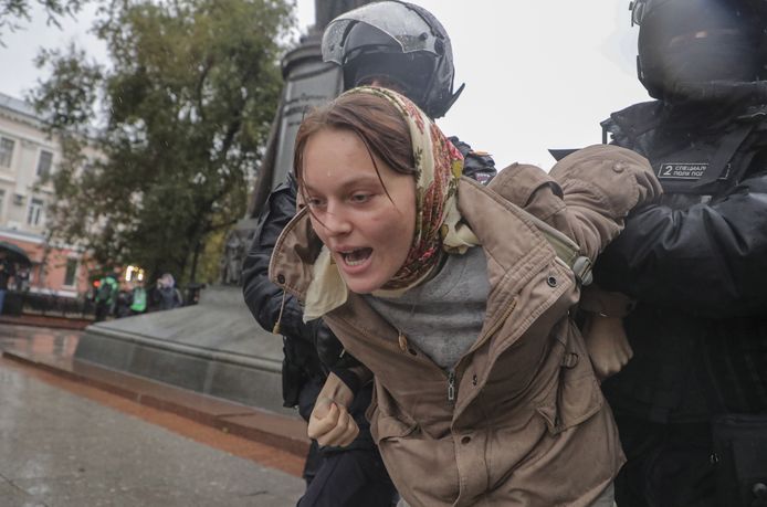 Russische politiemannen houden een vrouw in bedwang die protesteert tegen de mobilisatie van reservisten.