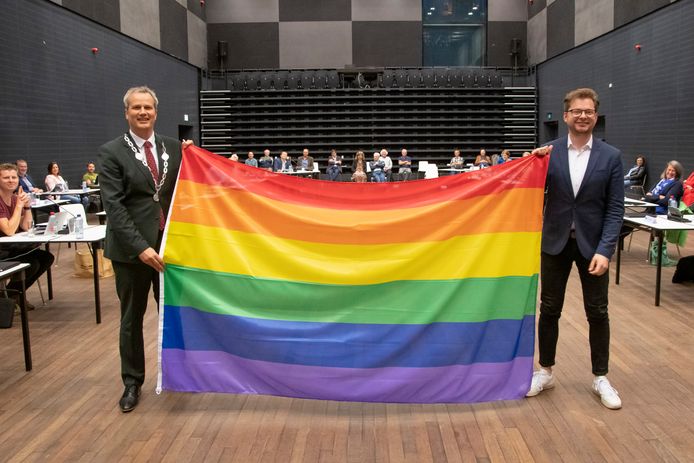 Burgemeester Evert Weys (l) en Tycho Holleman (VVD) poseren met de regenboogvlag tijdens de gemeenteraad. Zie kader verderop in de tekst.