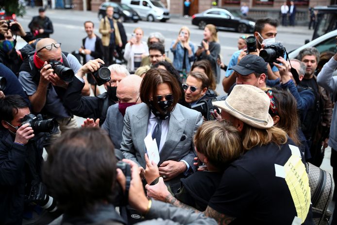 Johnny Depp (midden, in het grijze pak) wordt belaagd door pers en fans bij de rechtbank in Londen.