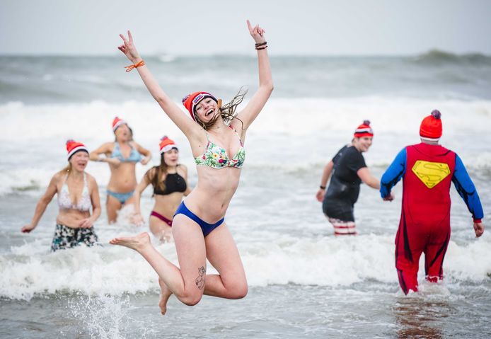 Deelnemers aan de traditionele Unox Nieuwjaarsduik rennen de Noordzee in voor een verfrissende duik.