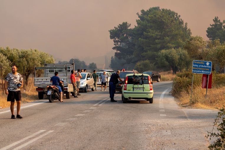 Toeristen en inwoners kijken naar een natuurbrand in de regio Kalamonas op Rodos. Beeld EPA