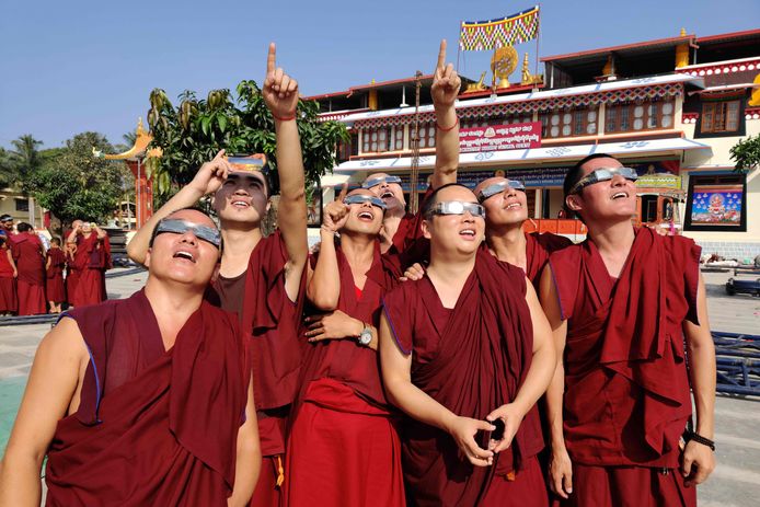 Monniken van een Tibetaans klooster in Teginkoppa in India bekijken de eclips door een beschermende bril.