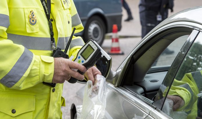 Een politieagent neemt een blaastest af tijdens een controle