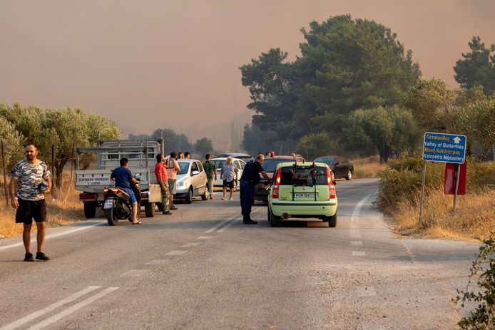Toeristen en inwoners kijken naar een natuurbrand in de regio Kalamonas op Rodos.