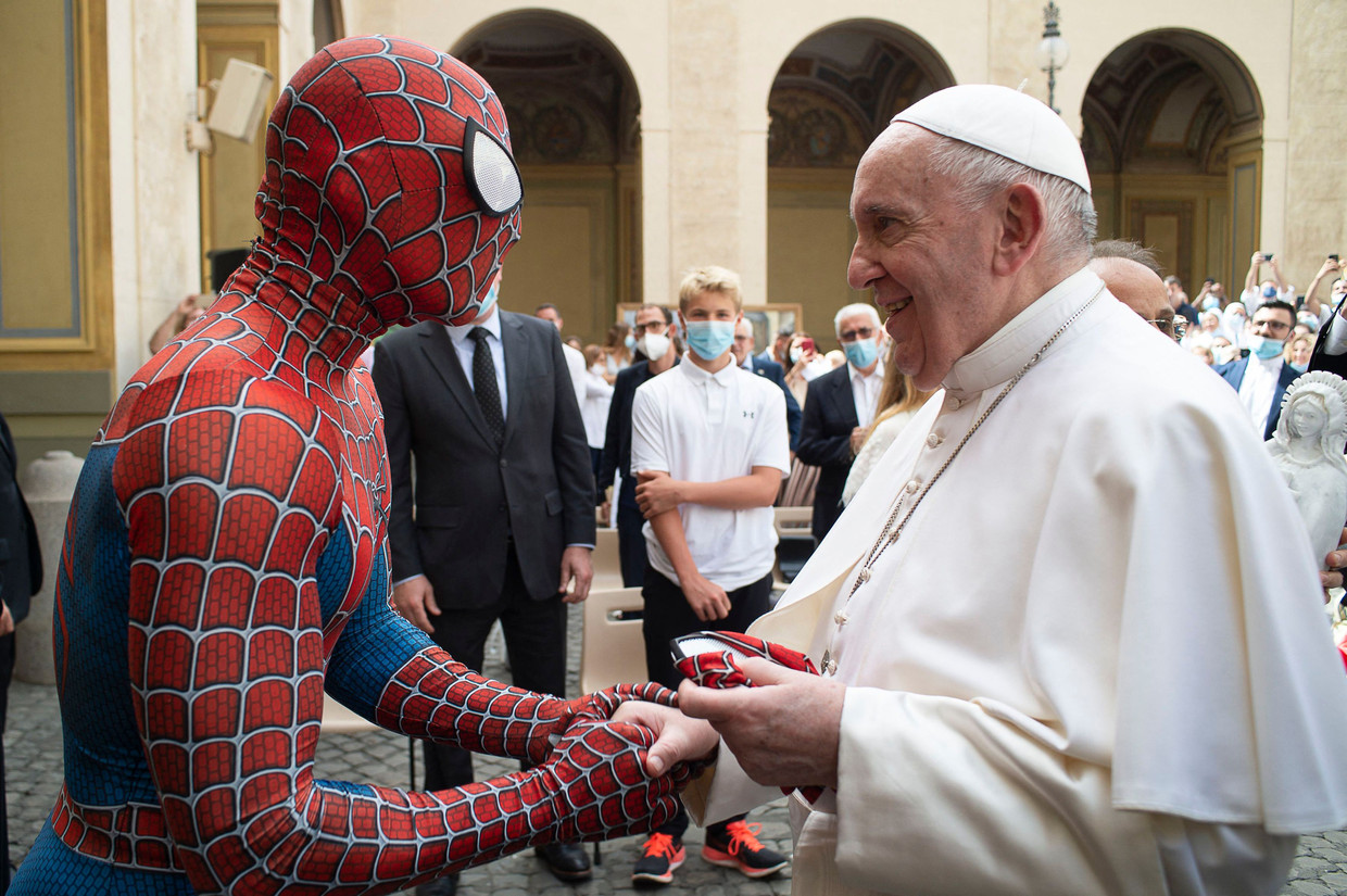 Paus Franciscus schudt een man de hand die als Spiderman optreedt voor kinderen in het ziekenhuis. Het Vaticaan wil dat de kerk op haar eigen manier pastoraal en educatief naar buiten kan blijven treden.  Beeld AFP