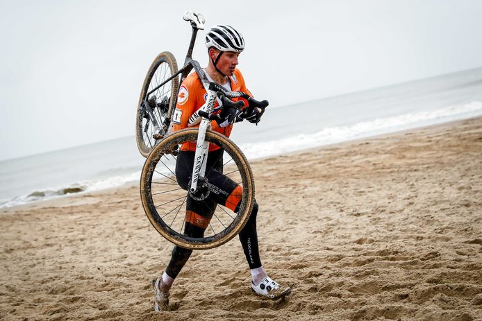 Mathieu van der Poel met de fiets aan zijn hand door het mulle zand in Oostende.