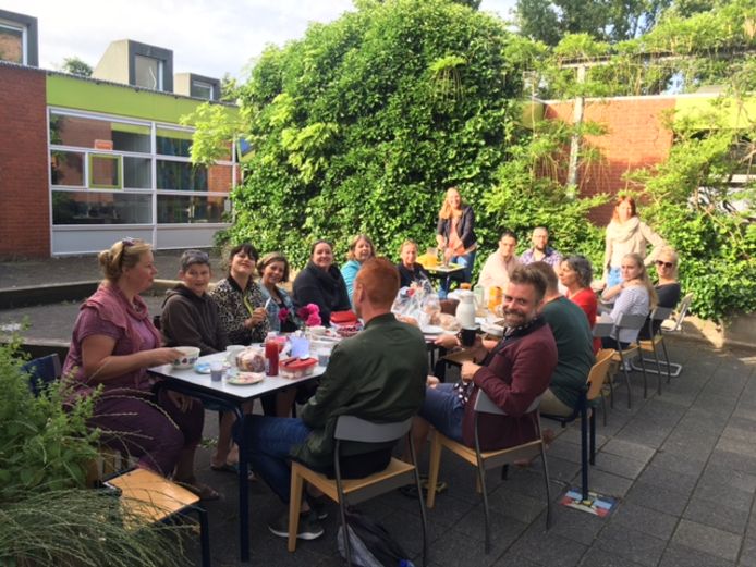 Leraren van basisschool De Carrousel in Gouda zitten in de tuin te ontbijten.