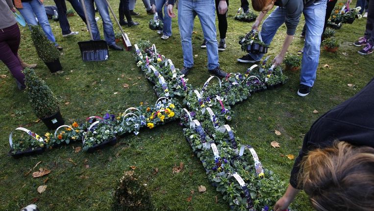 Groningse studenten maken met viooltjes de letter X op de plek waar het Project-X-feest in Haren uit de hand liep. Beeld anp