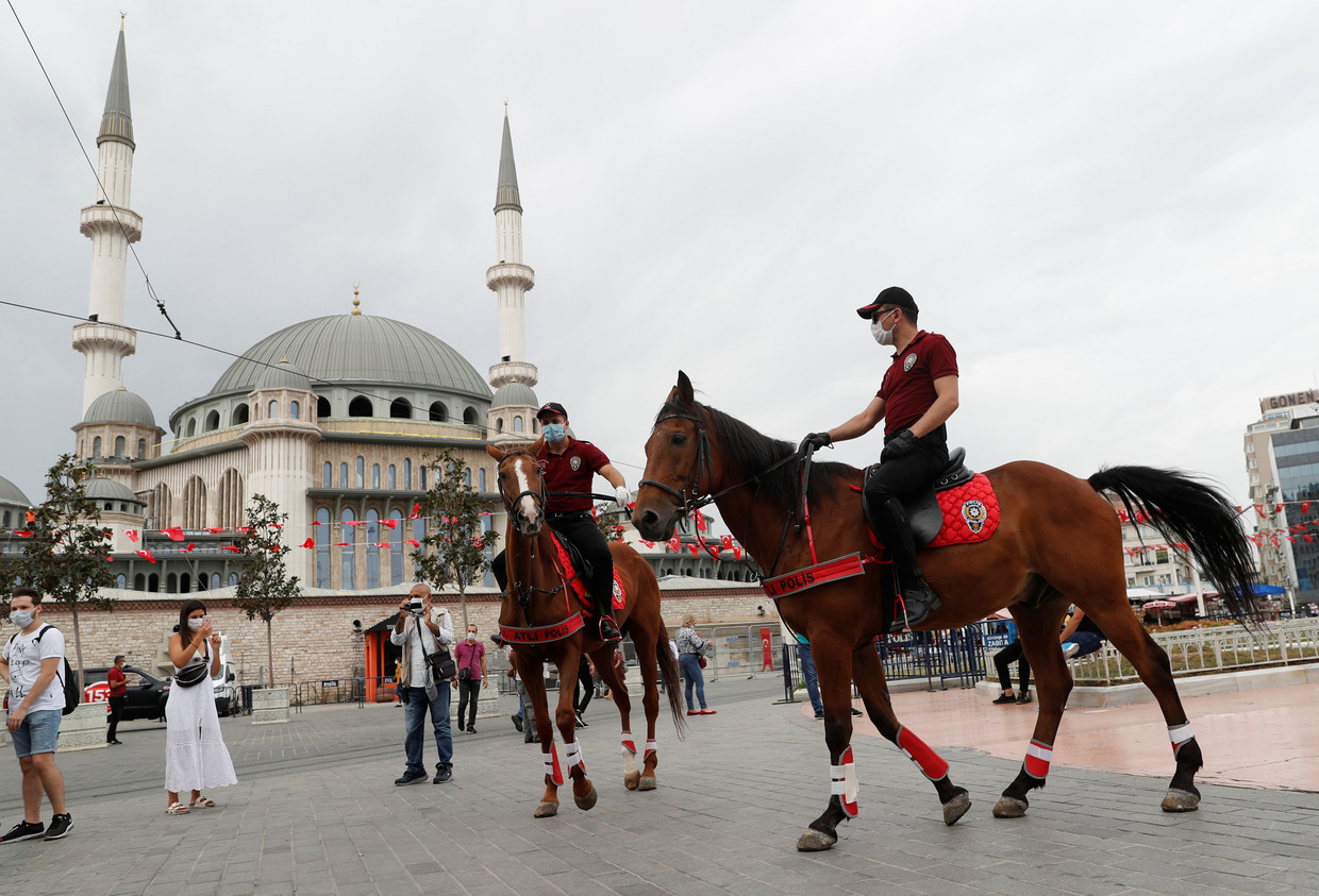 Turkse politieagenten te paard controleren op het Taksimplein in Istanbul op het dragen van een mondkapje.  Beeld REUTERS