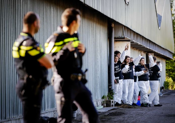 De actievoerders staan binnen, terwijl de politie toekijkt.