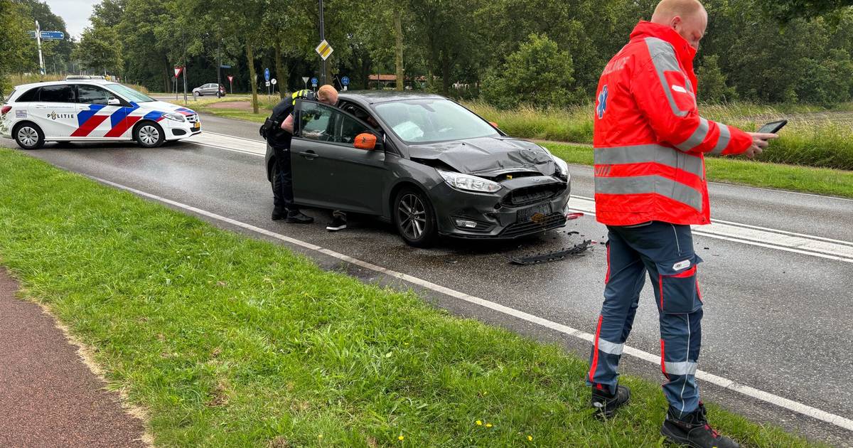Delen van bumper breken van auto af bij botsing met kleine vrachtwagen, bestuurders in ambulance.