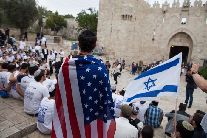 Een man draagt de Amerikaanse vlag bij de Damascuspoort in Jeruzalem. Donald Trump zal vandaag niet aanwezig zijn bij de opening van de Amerikaanse ambassade in Jeruzalem.