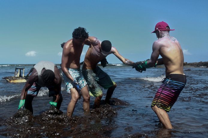 Vrijwilligers zitten onder de olie terwijl ze die proberen te verwijderen uit de zee bij Cabo de Santo Agostinho in de staat Pernambuco.
